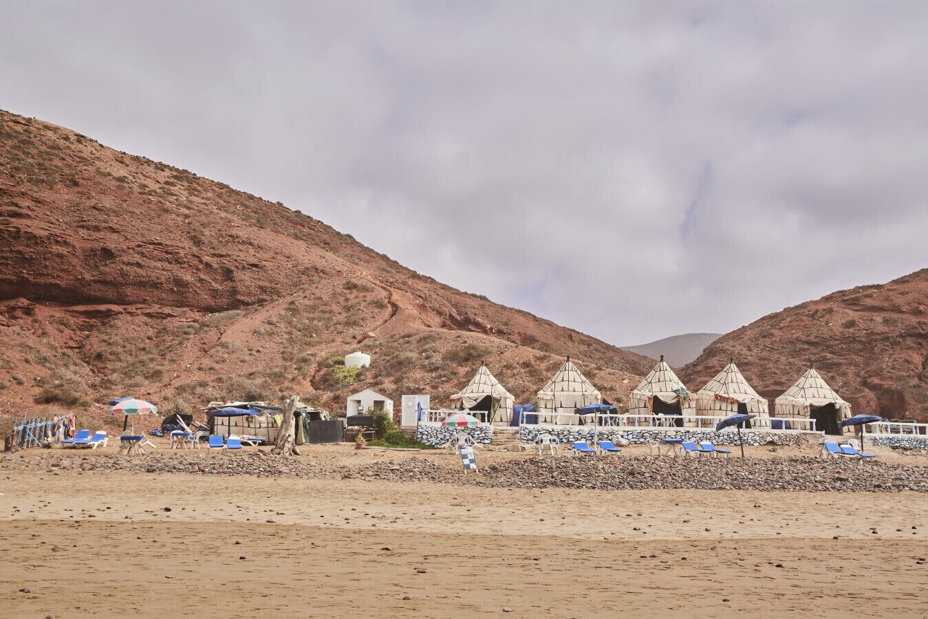 Un paysage désertique avec des tentes et des chaises de plage.