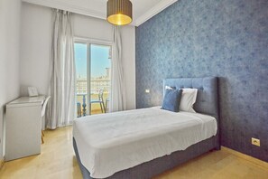 Un dormitorio con una cama grande, un escritorio y vistas a la ciudad a través de una ventana.