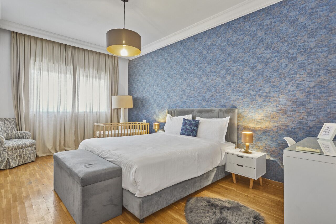 Une chambre à coucher avec un grand lit, une table de chevet avec une lampe, une chaise et un berceau.