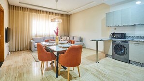 Um apartamento moderno com área de refeições, sofá, cozinha e máquina de lavar.