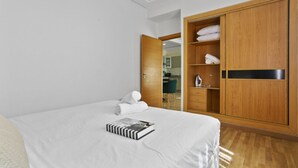 Una habitación de hotel con una cama grande, un armario de madera y un baño visible a través de una puerta abierta.