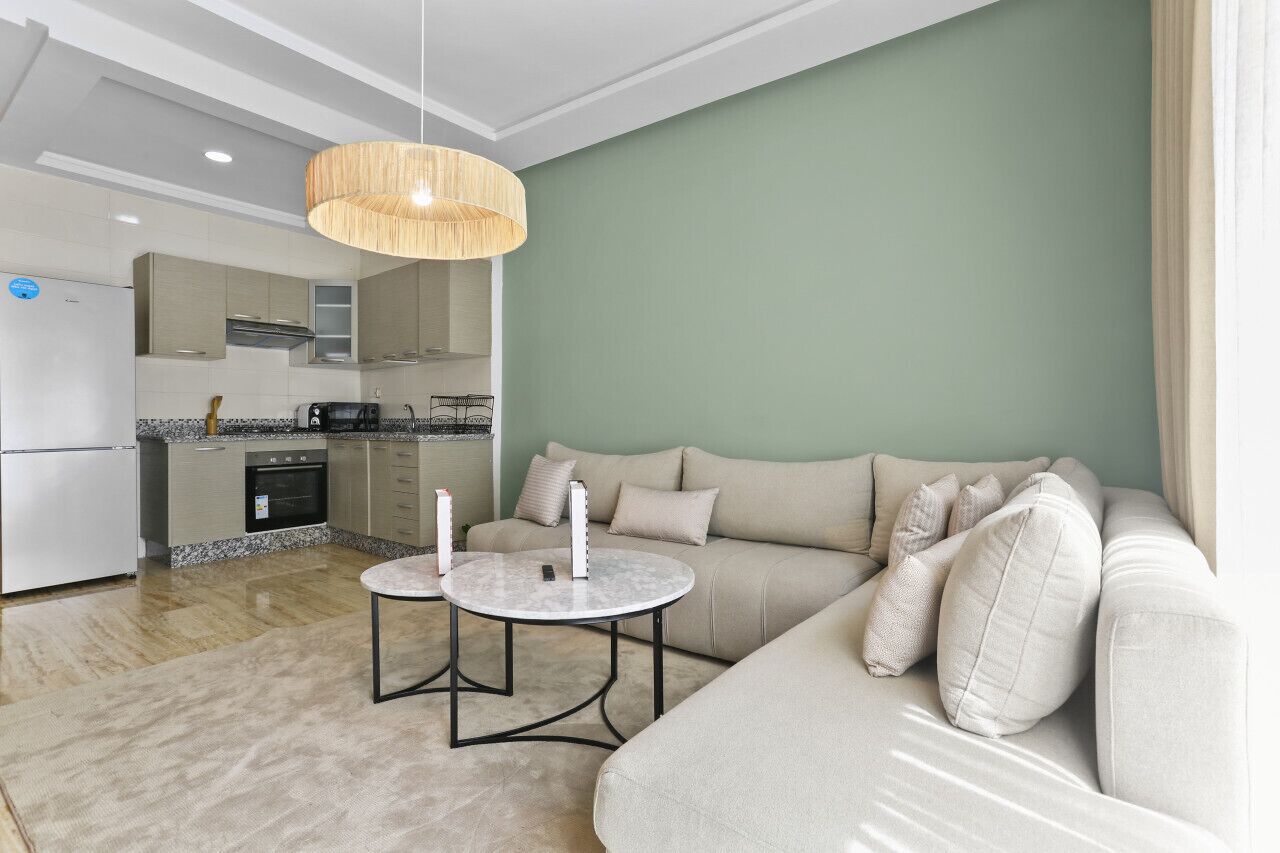 Ett modernt vardagsrum med en soffa, två runda bord och en hängande lampa.