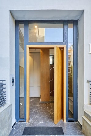 A modern entrance with a glass door, a wooden door, and a metal gate. - Sleek and Modern 2-Bed Unit in Downtown Casa (Casablanca)