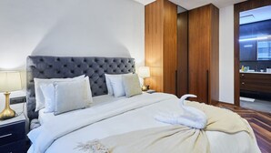 Ein Hotelzimmer mit einem gebügelten Kopfende, einem Bett mit weißer Bettwäsche, einem Holzschrank und einem Spiegel.