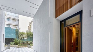 Ein modernes Gebäude mit Innenhof, einer Holz-Lamellenwand und einem Eingang mit Glasdoor.