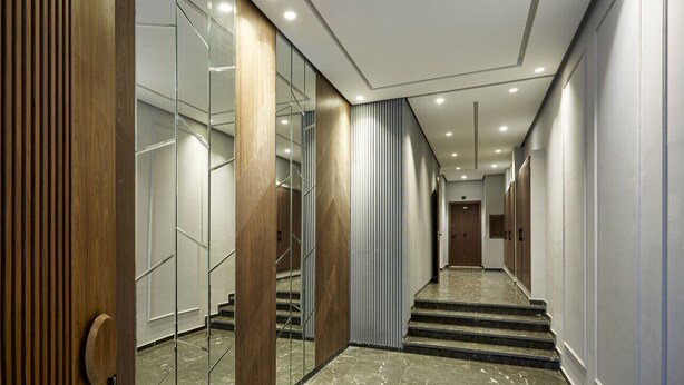 Ein moderner Hotelkorridor mit Glaswänden, Holzelementen und einem Marmorboden.