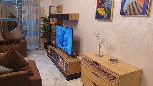 Een moderne woonkamer met een flatscreen televisie, een houten kast en een bank.