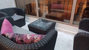Een zithoek buiten van riet met een glazen tafel en comfortabele fauteuils.
