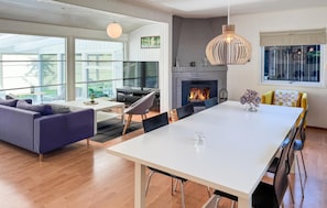 A modern living room with a fireplace, a dining area, and a sofa.