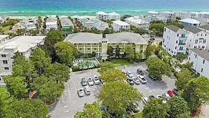 A coastal residential area with multiple apartment buildings, a parking lot, and a view of the ocean. - Grand Isle Condo 306 (Santa Rosa Beach)