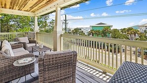 A covered outdoor seating area with wicker furniture and a view of the neighborhood. - Grand Isle Condo 306 (Santa Rosa Beach)