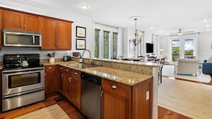 A modern kitchen with granite countertops, stainless steel appliances, and wooden cabinets. - Grand Isle Condo 306 (Santa Rosa Beach)