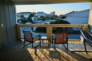 A balcony with two wicker chairs, a small table, and a hammock. - 3BR Coastal Retreat – 1 minute walk to beach - Free parking for 3 (Panama City)