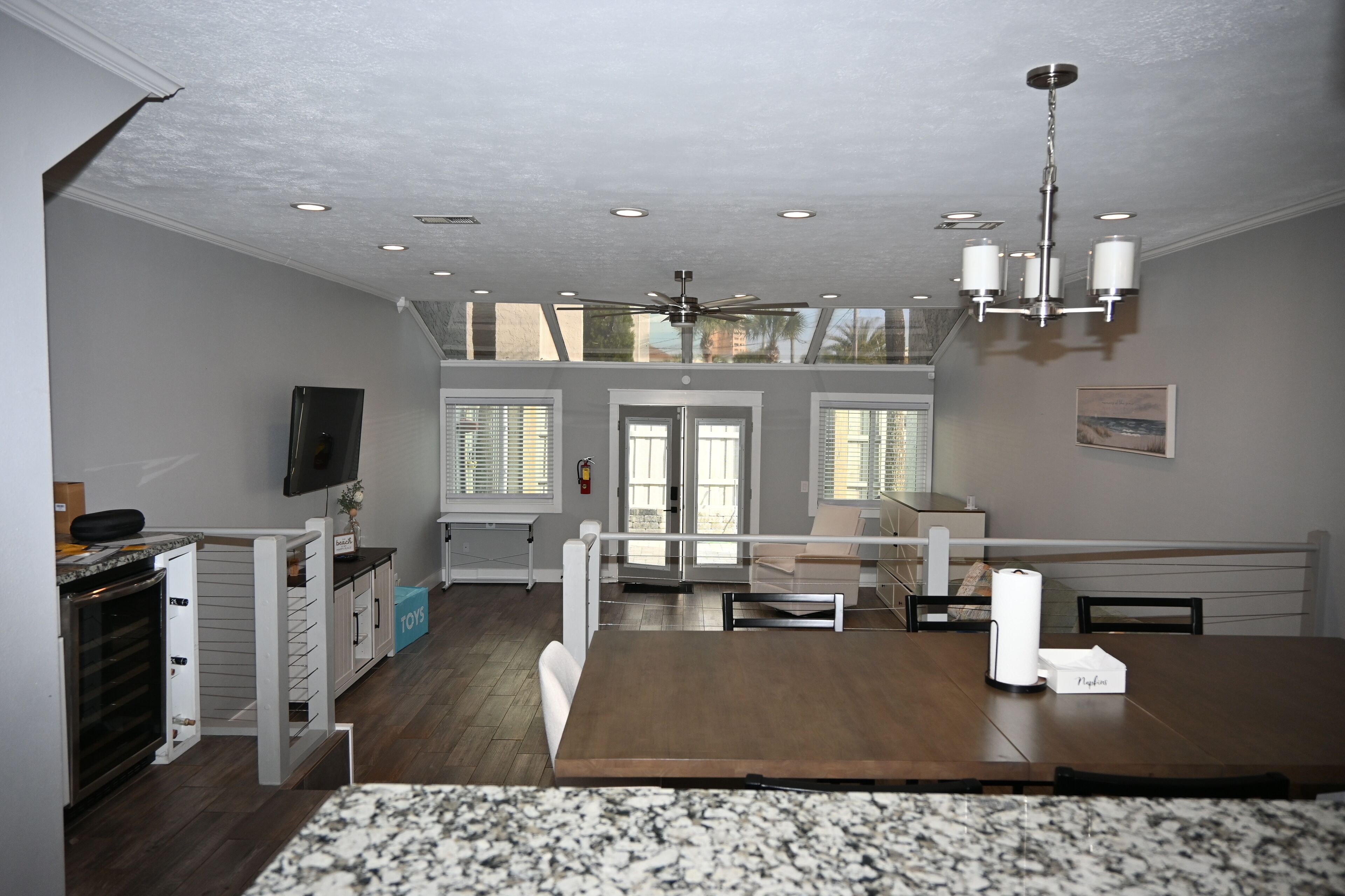 A spacious kitchen with a wooden table, white cabinets, and a ceiling fan.