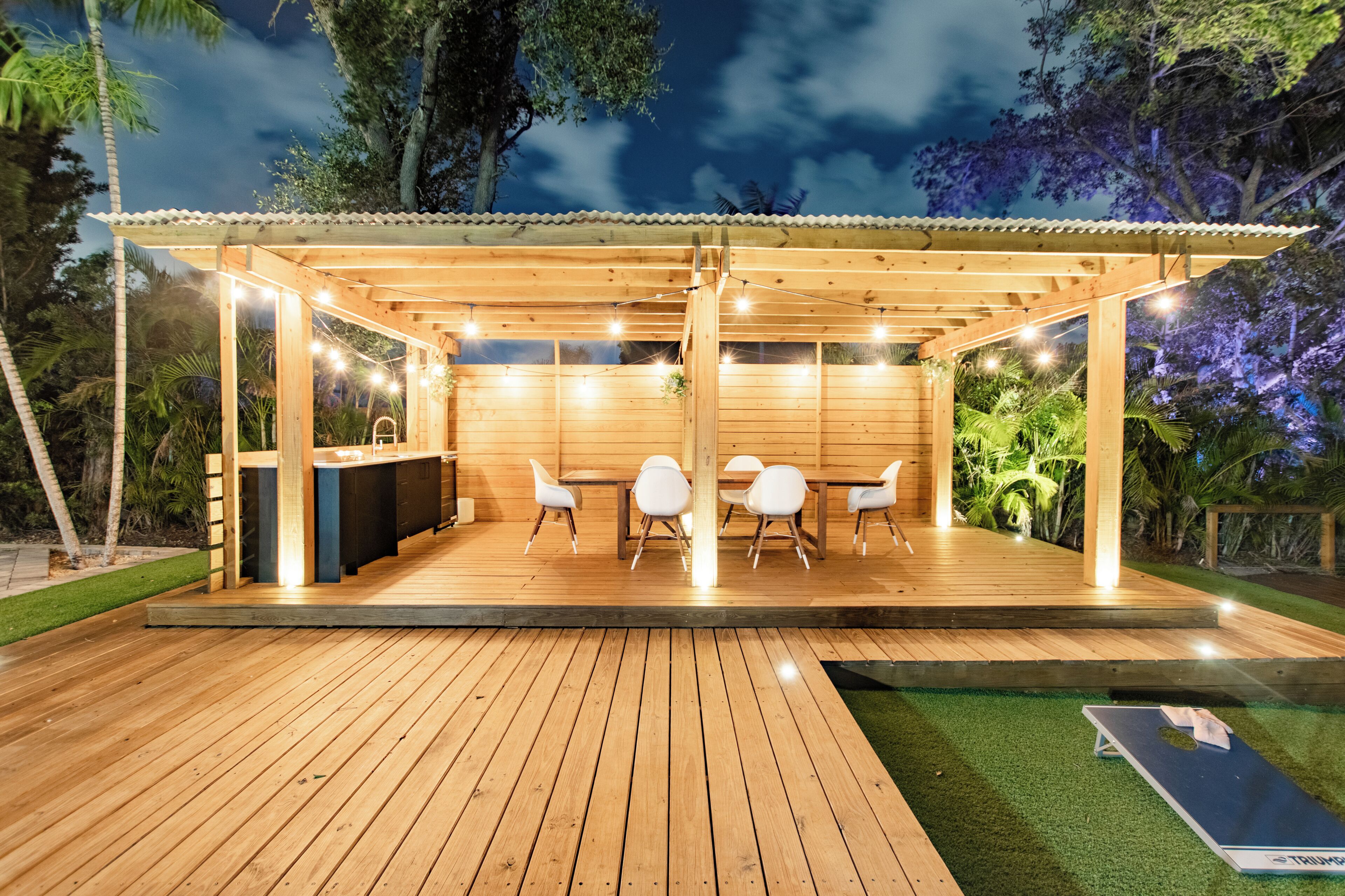An outdoor wooden deck with a pergola, a bar area, and seating.
