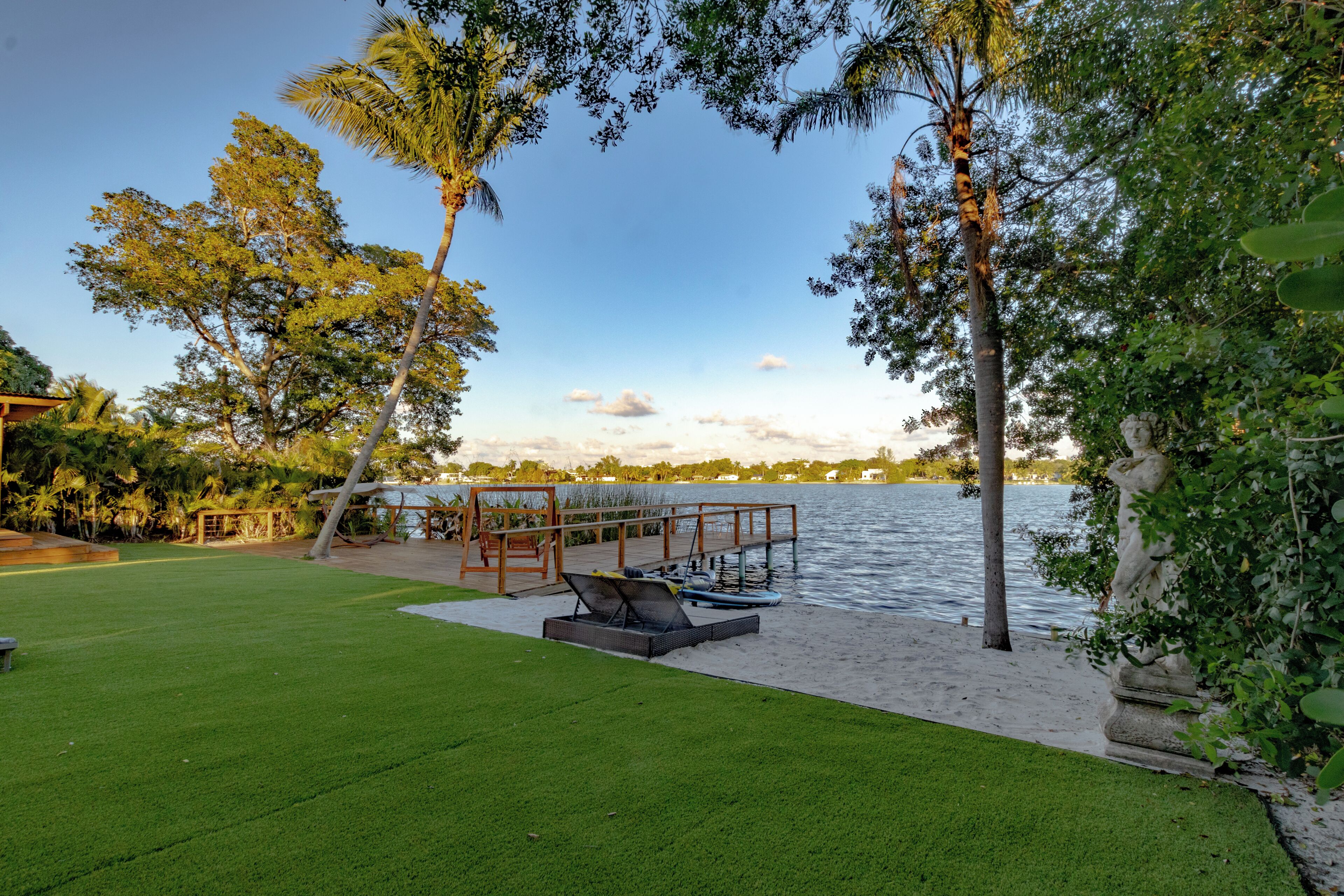 A waterfront property with a grassy lawn, a wooden deck, and a view of the water.