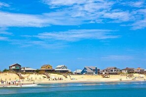 Ein Strandgrundstück mit mehreren Häusern, einem Sandstrand und blauem, klarem Himmel.