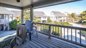 En träveranda med en stol, med utsikt över en bostadsgata med hus och parkerade bilar.