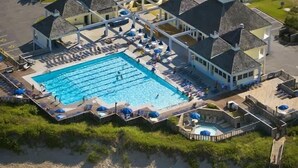 En vy från ovan av ett semesterområde med en stor pool, flera avslappningsområden och en täckt terrass.