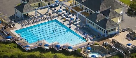 Vista aérea de un resort con una gran piscina, varias zonas de descanso y una terraza cubierta.