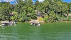 A lakeside property with docked boats, a small dock structure, and houses surrounded by dense trees. - Sundance - Lakefront w/ Private Dock (Moneta)