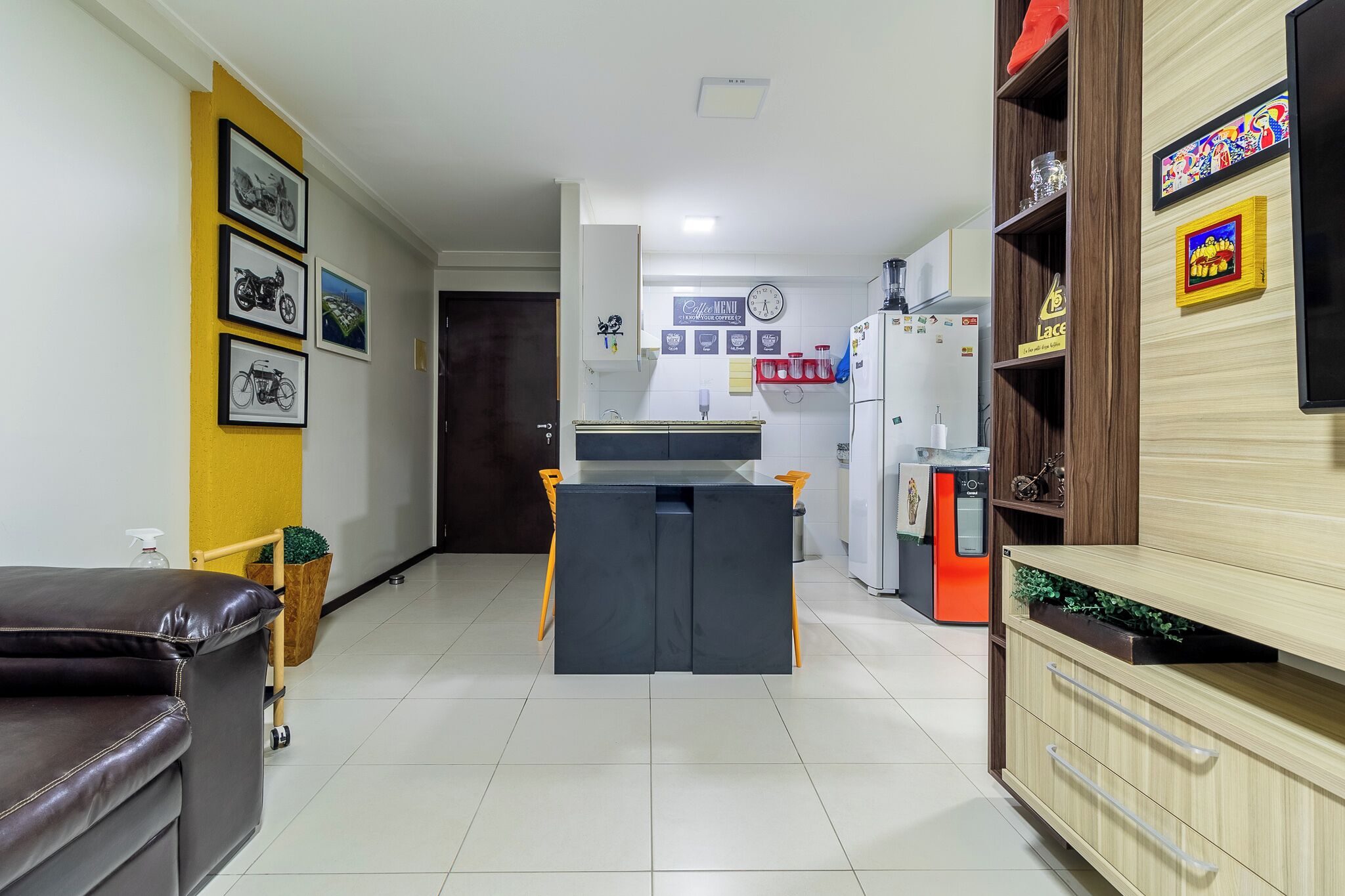 Una cocina moderna con una isla central, un refrigerador y una zona de comedor con sofá.