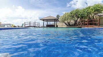 Una piscina al aire libre, sombrillas, sillones reclinables de piscina