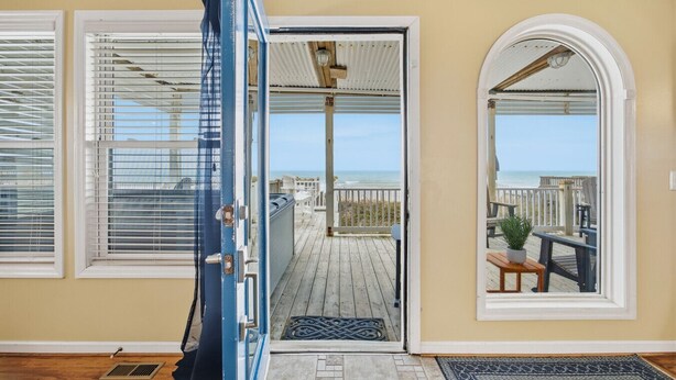 Una habitación con vista a una terraza de madera y a la playa.