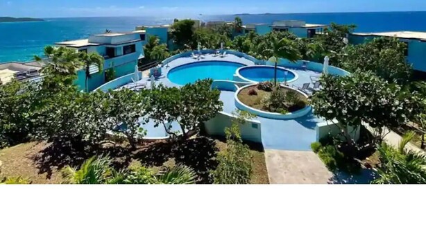Ein Resort mit großem Pool, umgeben von Grünflächen und Gebäuden.