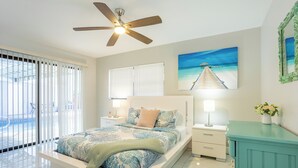 A bedroom with a bed, nightstands, a ceiling fan, a painting, a mirror, and a teal cabinet. - Peaceful 4-bedroom house with AC and Heated Pool in charming Largo Florida (Largo)