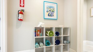 A hallway with a fire extinguisher, a framed picture, and a storage unit with towels. - Peaceful 4-bedroom house with AC and Heated Pool in charming Largo Florida (Largo)