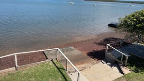 A lakeside view with boats, a grassy area, and a concrete walkway leading to a dock. - Room-salt and Sea Renity On Milton (Russell Island)