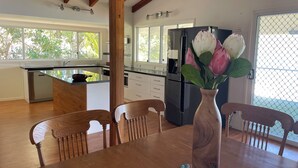 A modern kitchen with a central island, wooden dining table, and chairs. - Room-salt and Sea Renity On Milton (Russell Island)