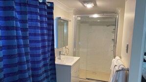 A bathroom with a shower, sink, and a towel rack. - Room-salt and Sea Renity On Milton (Russell Island)
