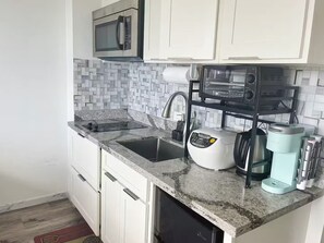 Une cuisine moderne avec des meubles blancs, un four à micro-ondes, une machine à café et un lave-vaisselle.
