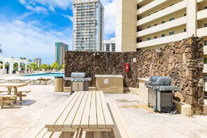 Une terrasse extérieure avec un mur en pierre, une piscine et un espace barbecue.