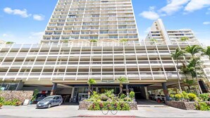 A tall hotel with multiple balconies and a covered entrance. - Waikiki Seaside Luxury King Condo with Balcony (Honolulu)