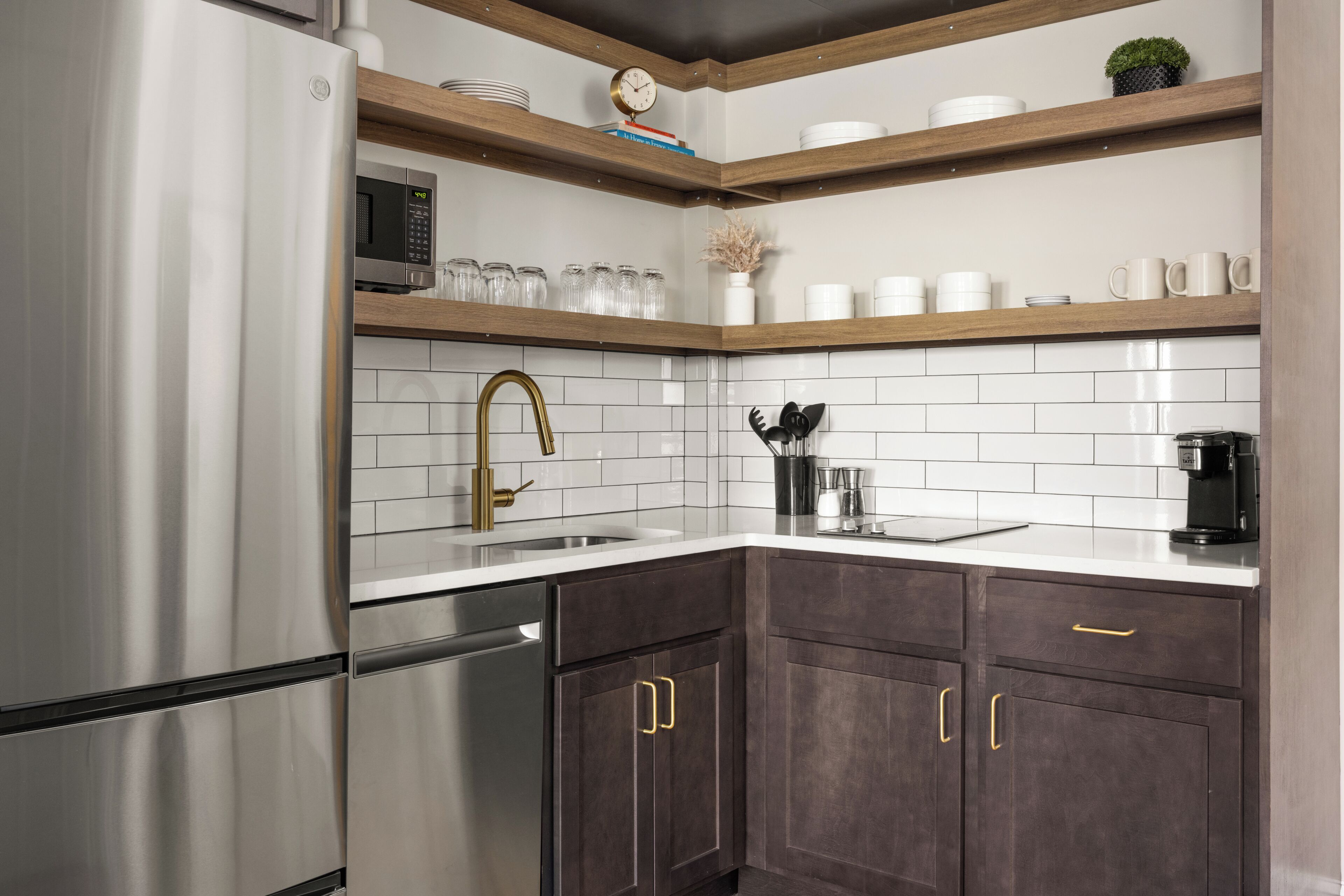 A modern kitchen with stainless steel appliances, dark wooden cabinets, and white tiled backsplash.