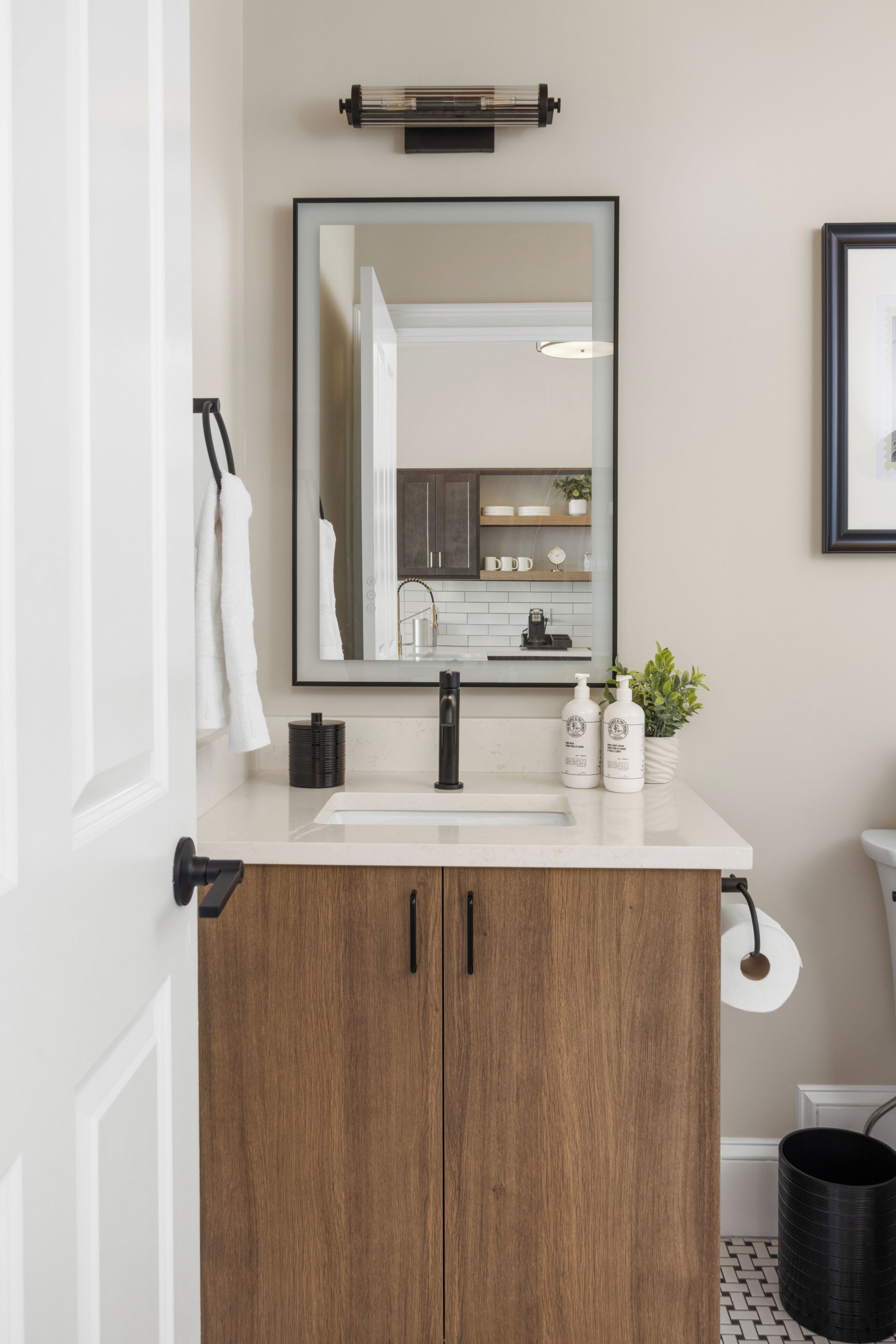 A bathroom with a wooden vanity, a mirror, a sink, and a toilet.