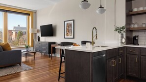 Une cuisine moderne dotée d’un grand îlot central, de meubles de rangement aux couleurs sombres et de luminaires suspendus.