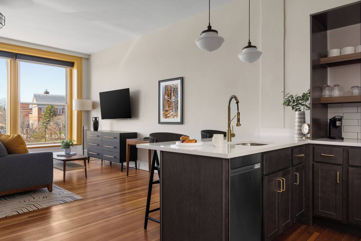 Una cucina moderna con una grande isola, mobili scuri e luci a sospensione.