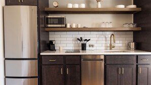 Une cuisine moderne avec des meubles de couleur sombre, des appareils électroménagers en acier inoxydable et des étagères en bois.