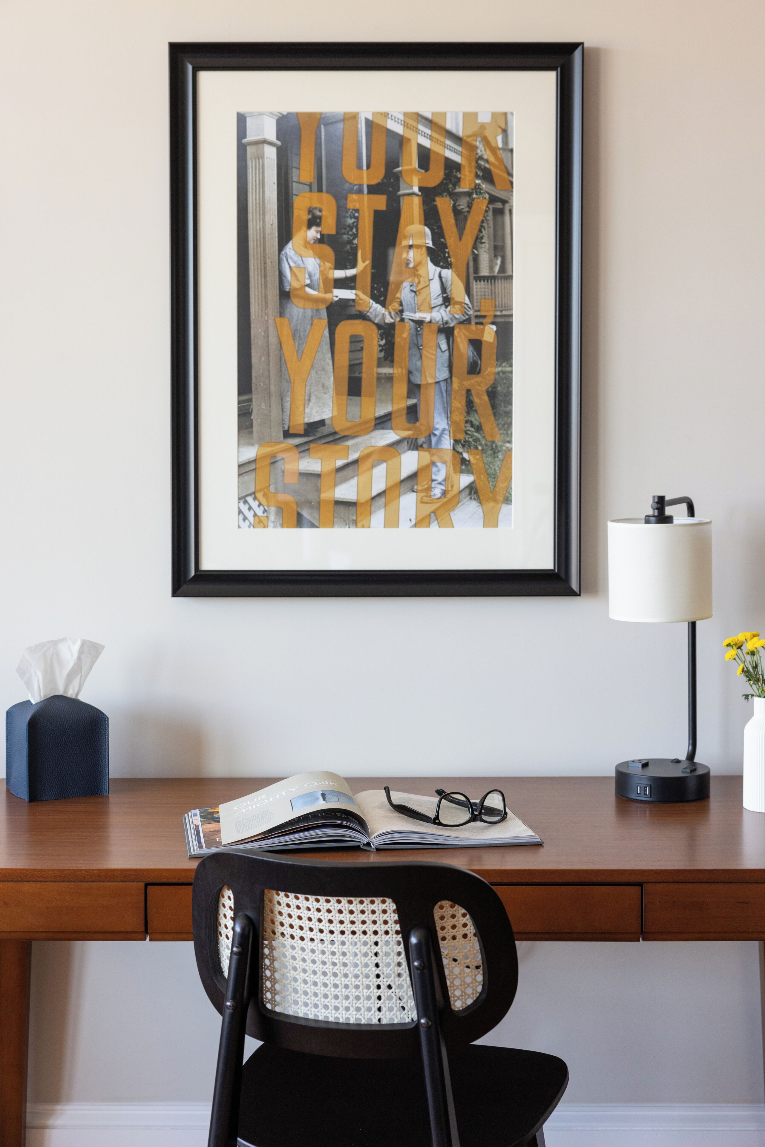 A framed motivational quote on a wall, a desk with a chair, a lamp, and a tissue box.
