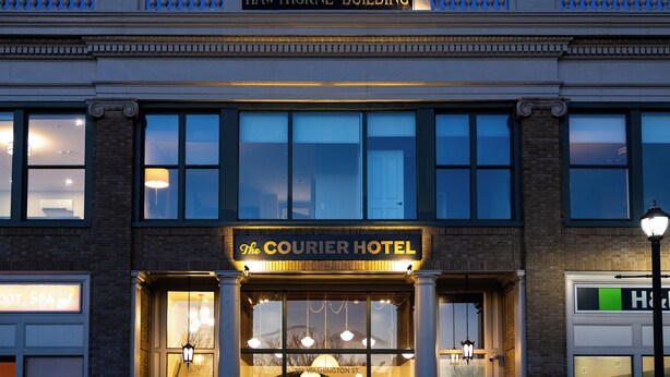 Un immeuble portant une enseigne indiquant « HAWTHORNE BUILDING » et « THE COURIER HOTEL », avec l’adresse clairement visible : « 201 WASHINGTON ST. »