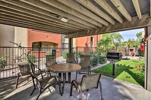 A shaded patio with a dining table and chairs adjacent to a barbecue grill and lawn. - Papago Park Condo w/ Pool & Hot Tub (Phoenix)
