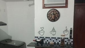 A kitchen area with a black refrigerator, a gas stove, a coffee machine, and a small bar counter with two stools. - UNIVERSIFLAT Ponta Grossa. (Ponta Grossa)