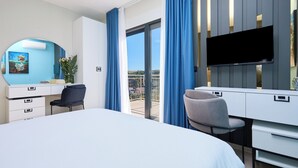 Een hotelkamer met een bed, een bureau met stoel, een televisie en een balkon met uitzicht.