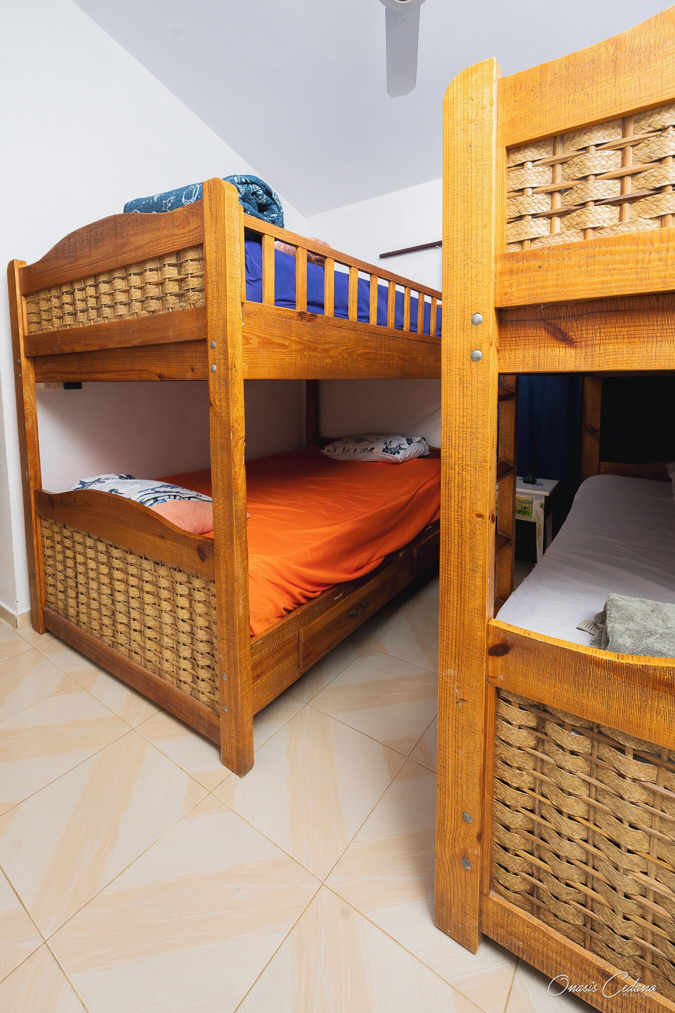 A bunk bed with a woven headboard and a lower bunk with a blue blanket.