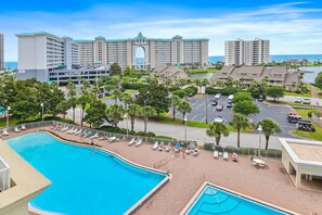 A hotel with a large swimming pool, multiple buildings, and a view of the ocean. - Ariel Dunes II 607 (Miramar Beach)