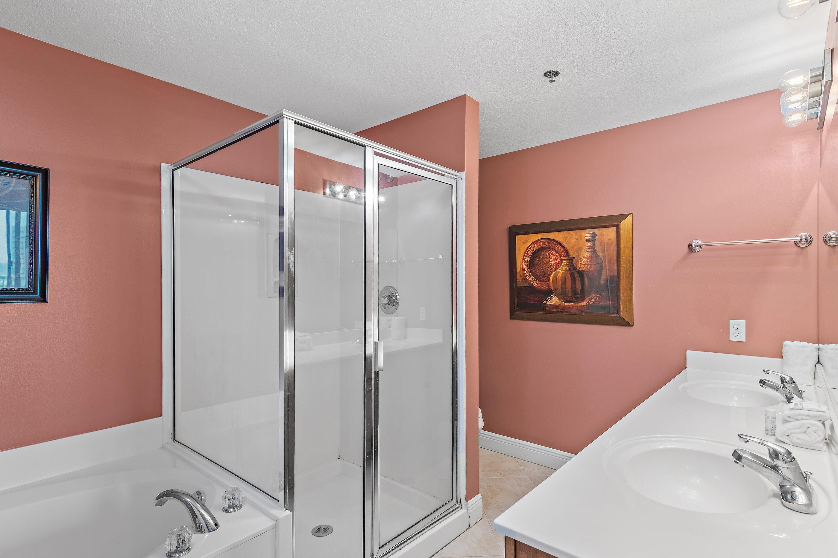 Une salle de bain avec une douche à parois de verre, deux lavabos et un porte-serviettes.